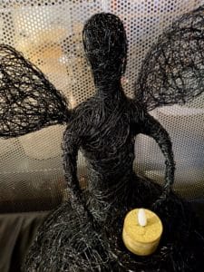 Sitzender Drahtengel Schwarz auf Lederoberfläche