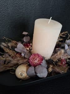 Trockenblumen-Arrangement mit Kerze in Bordeaux, Braun und Hellrosa in harmonischer Naturkomposition