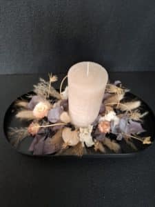 Trockenblumen-Arrangement mit Kerze in Pastelltönen und Braun auf ovalem Untergrund